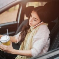 Busy woman is in a hurry, she does not have time, she is going to worck on the go. Worker is drinking hot coffee, writing in a notebook and talking on the phone at the same time. Business female person. She multitasking while using on the phone and driving a car